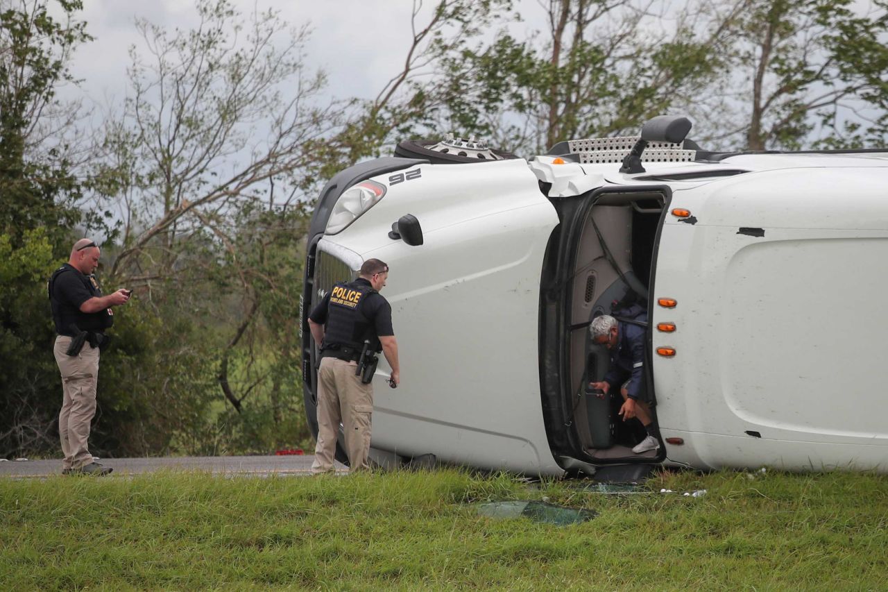 The driver of an overturned 18-wheeler exits his vehicle after police arrive to the scene along Interstate 10 in Vinton, Texas. Both the driver and a passenger suffered minor injuries.