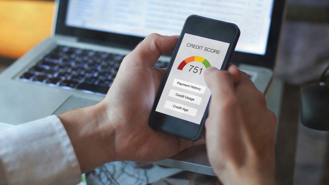 A hand holding a smartphone with a credit score on the screen.