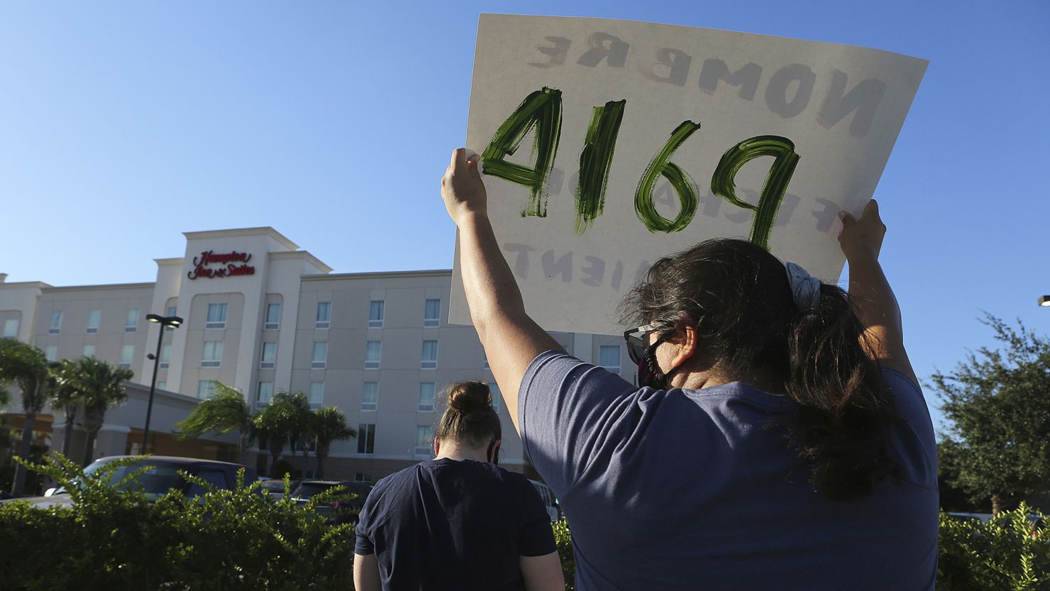 Protesters wave signs in front of the Hampton Inn hotel in McAllen, Texas, where migrants were being detained, on July 23, 2020.