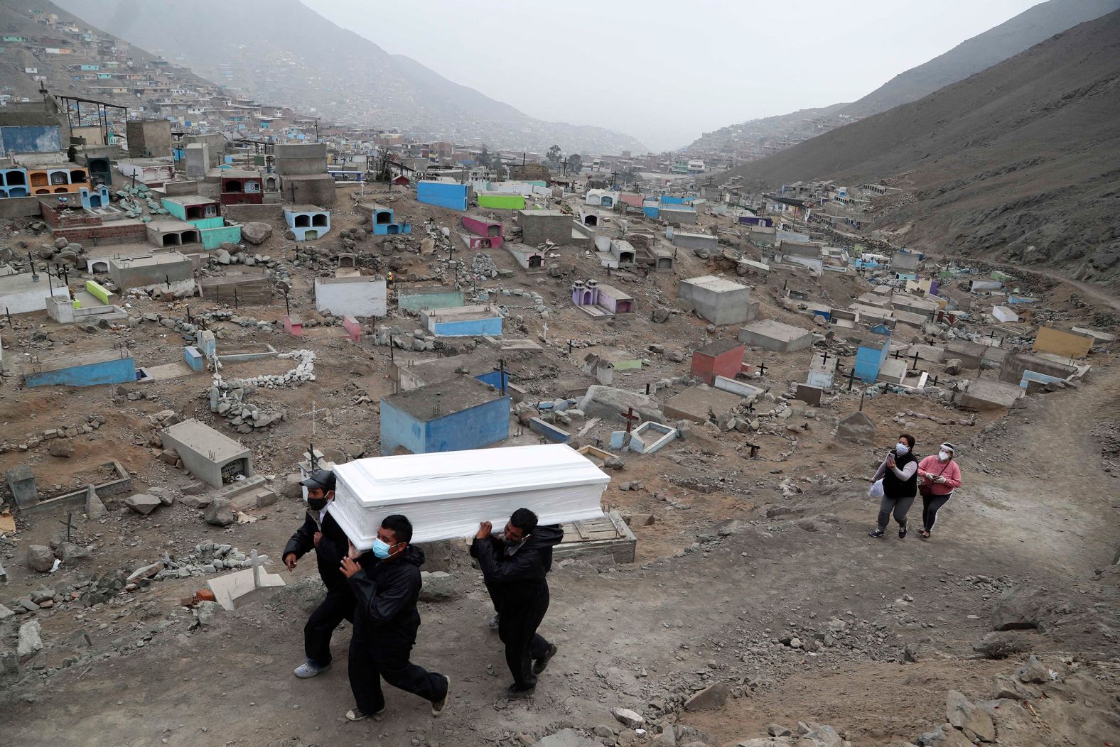 Cemetery workers carry Wilson Gil's remains on the outskirts of Lima, Peru, on August 26. Gil died of complications related to Covid-19, according to family members.