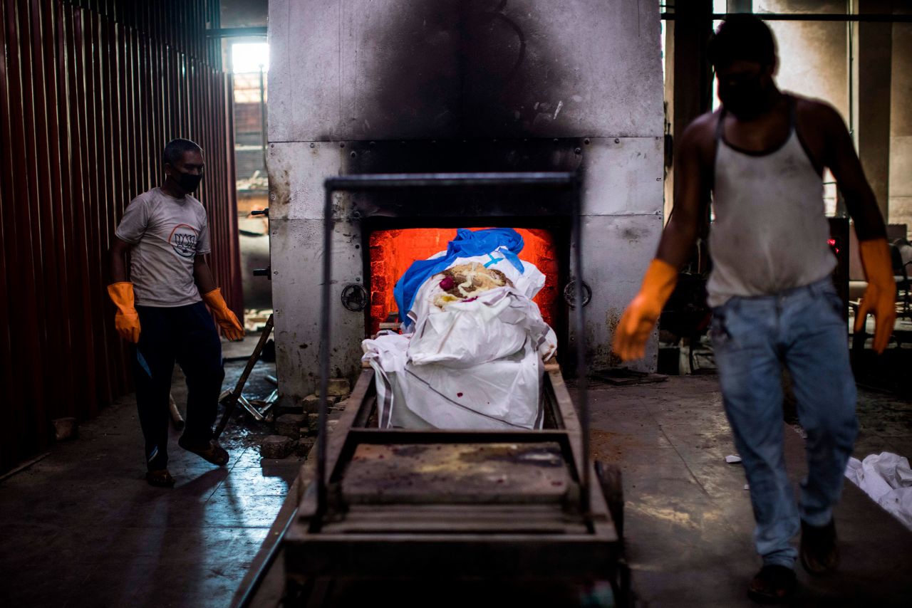 Workers in New Delhi prepare to cremate the body of a coronavirus victim on August 22.