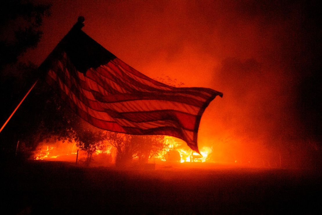 An American flag blows in the wind in front of a burning home in Vacaville, California, during the LNU Lightning Complex fire on August 19, 2020. 