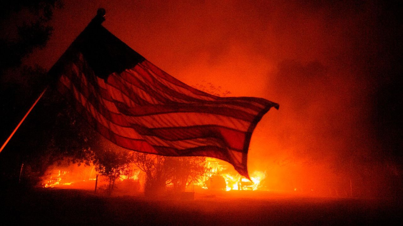 An American flag blows in the wind in front of a burning home in Vacaville, California, during the LNU Lightning Complex fire on August 19, 2020. 