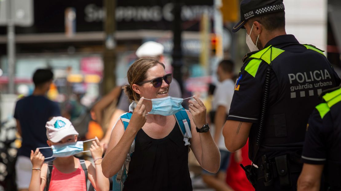 Catalonian police officers ask a woman to wear a face mask at Las Ramblas in Barcelona, Spain, on July 9, 2020.