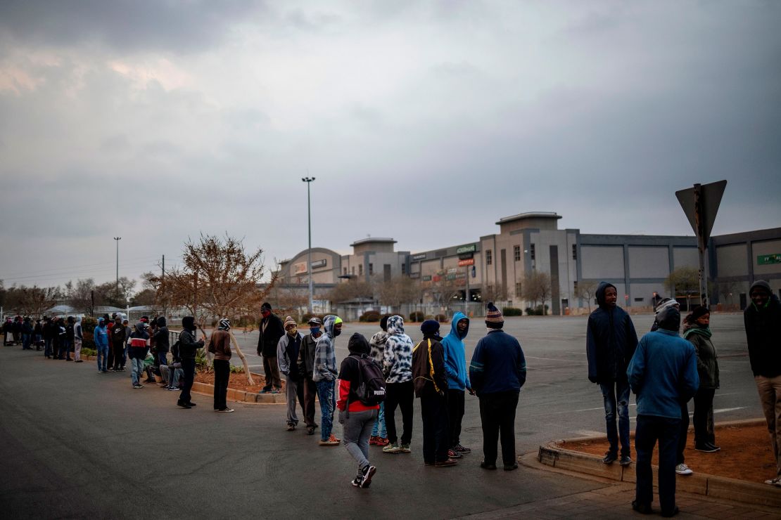 Customers queue while waiting for the opening of a liquor shop in Johannesburg, on August 18