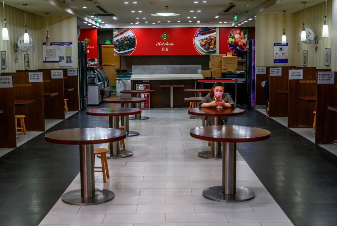 A Chinese woman wears a protective mask as she sits in a nearly empty restaurant at a shopping mall on March 26 during coronavirus restrictions in Beijing, China.