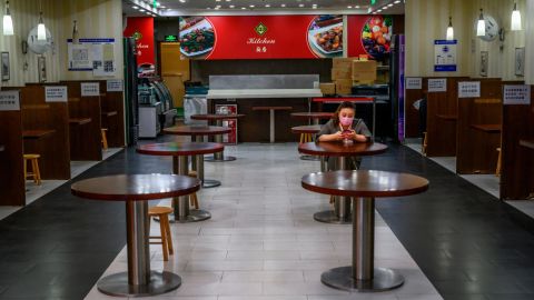 A Chinese woman wears a protective mask as she sits in a nearly empty restaurant at a shopping mall on March 26 during coronavirus restrictions in Beijing, China.