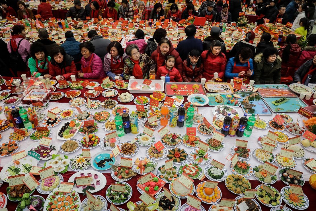Neighborhood residents sit around a table full of homemade dishes on February 9, 2018 in Wuhan, Hubei province, China, to celebrate the Lunar New Year.