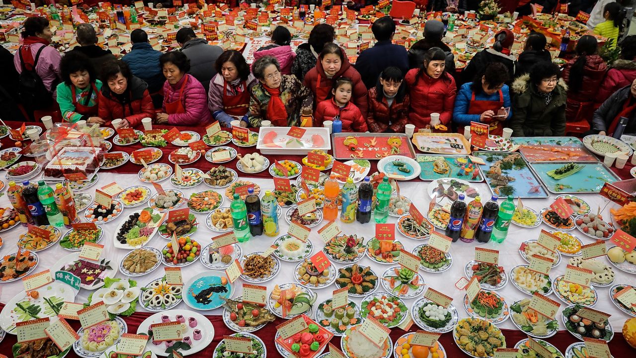 Neighborhood residents sit around a table full of homemade dishes on February 9, 2018 in Wuhan, Hubei province, China, to celebrate the Lunar New Year.