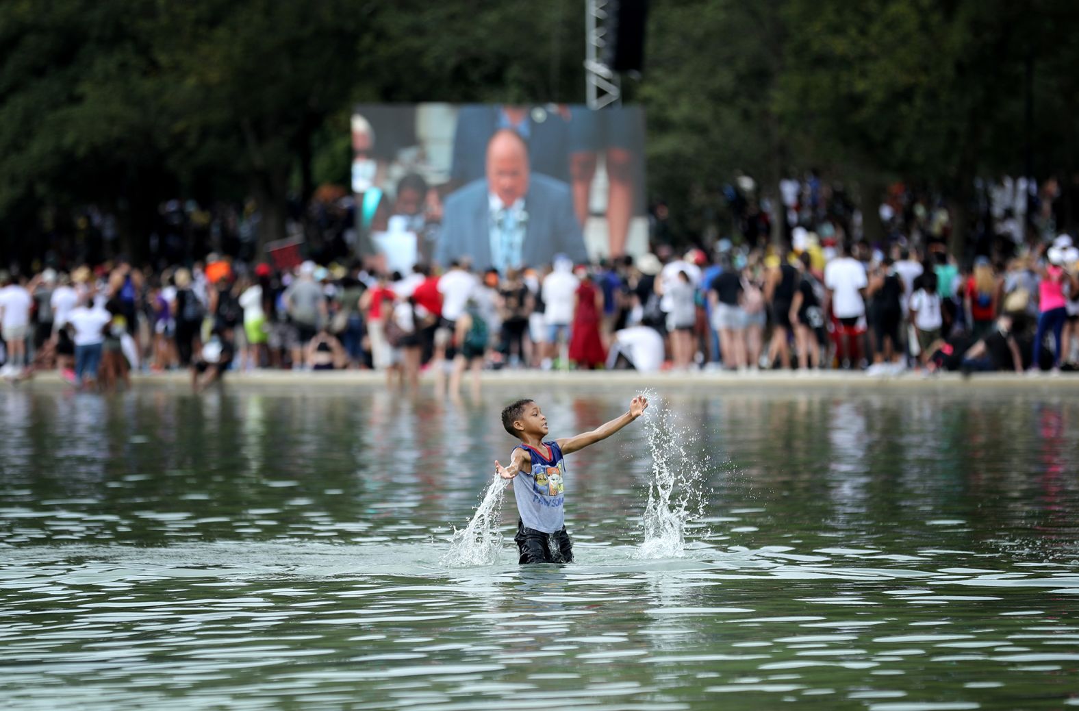 A boy cools off in the Lincoln Memorial's Reflecting Pool as Martin Luther King III speaks.