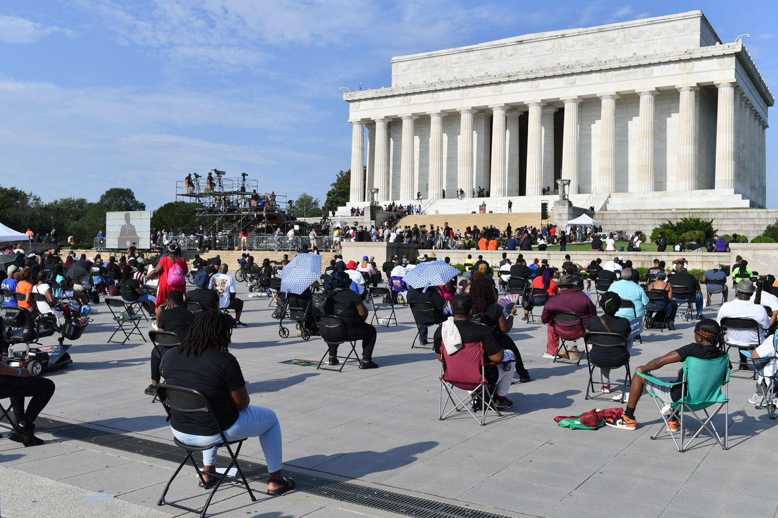 Attendees sit socially distanced from one another on the National Mall.