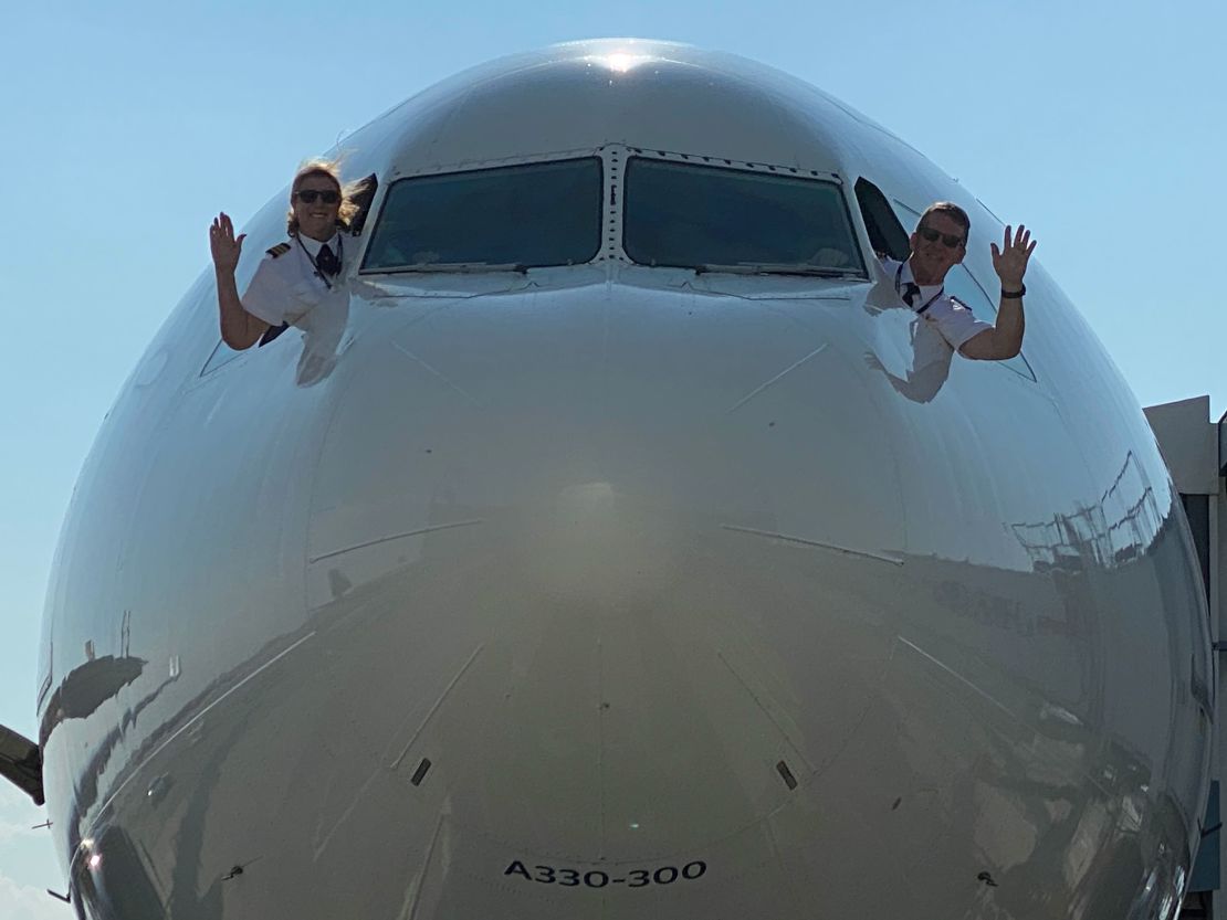 Joe and Margrit Fahan wave farewell from the flight deck of a Delta A330 