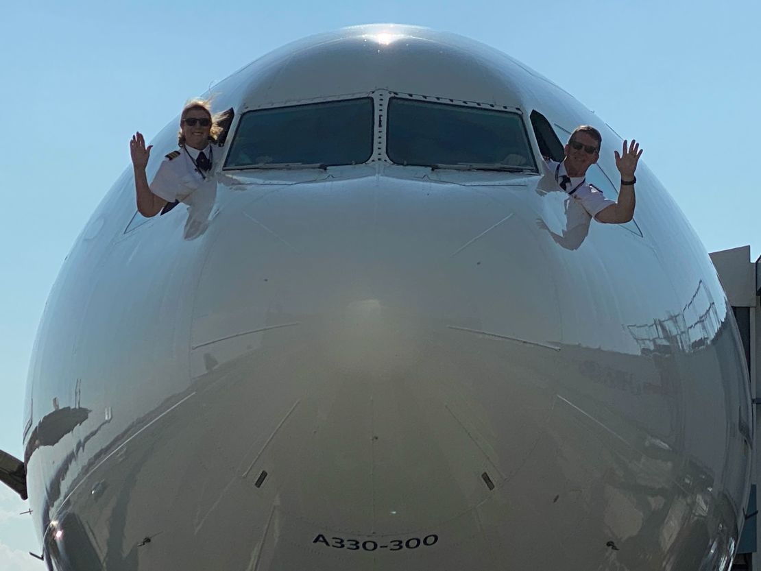 Joe and Margrit Fahan wave farewell from the flight deck of a Delta A330