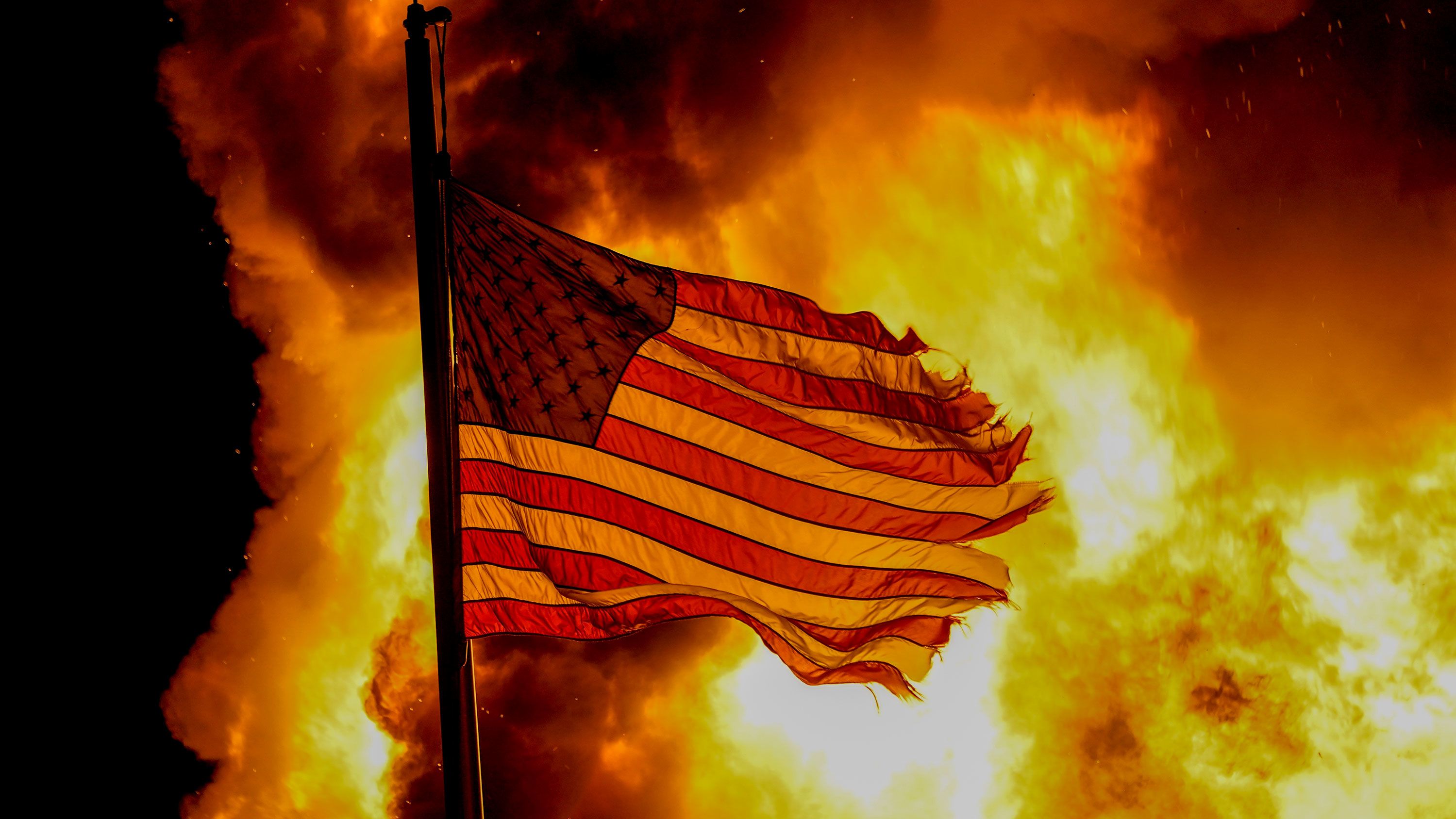 A flag flies over a department of corrections building ablaze during protests, late Monday, August 24 in Kenosha, Wisconsin, sparked by the shooting of Jacob Blake by a Kenosha Police officer a day earlier. 