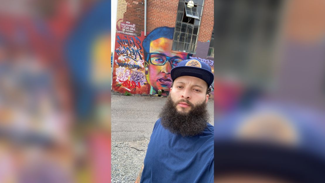 Elijah McKnight stands in front of a mural to Elijah McClain. Both encountered law officers and were injected with ketamine.