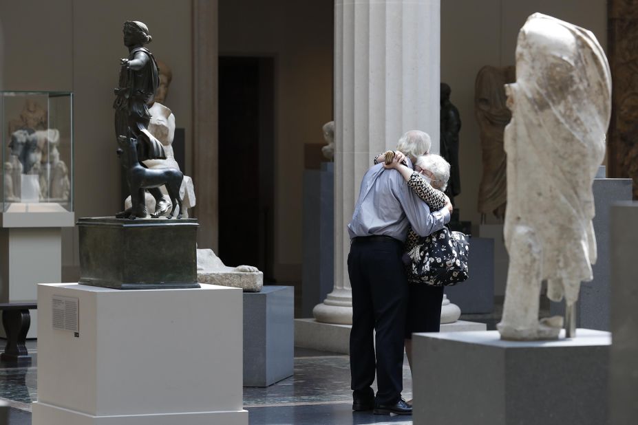 People wearing face masks hug at New York's Metropolitan Museum of Art as it reopens to members on August 27.