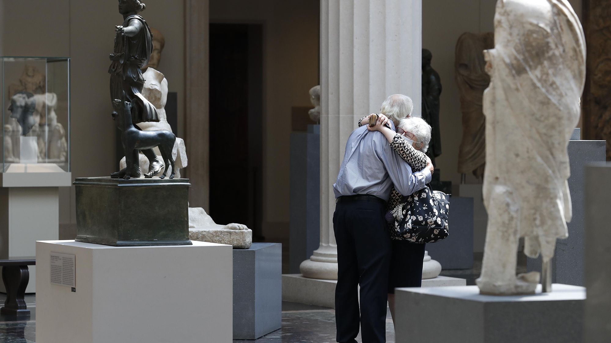 People wearing face masks hug at New York's Metropolitan Museum of Art as it reopens to members on August 27.