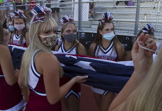 Cheerleaders from Herriman High School carry the American flag before a football game in Herriman, Utah, on August 13. The Herriman Mustangs faced the Davis Darts in the first high school football game in the country this season.