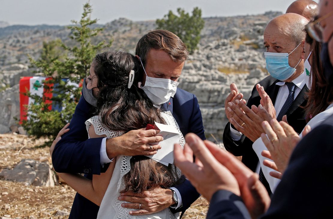 The French President hugs a blast victim while attending a ceremony, with French Foreign Minister Jean-Yves Le Drian (right) to mark Lebanon's centenary in Jaj Cedars Reserve Forest, northeast of Beirut, on September 1.
