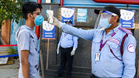 A student gets their temperature taken at an examination center in Noida, India.
