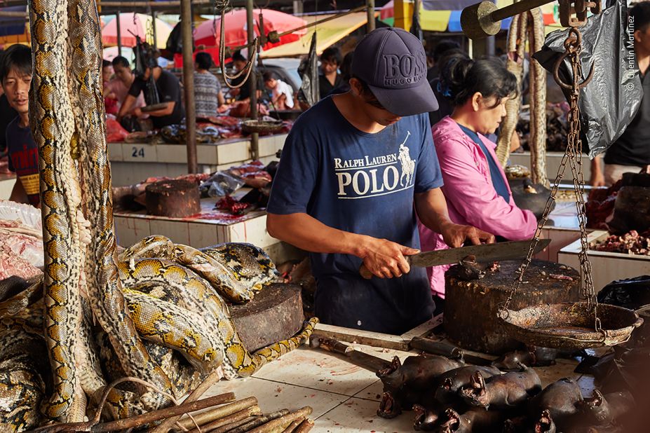 A market trader in Indonesia slices up fruit bats at his stall, which also stocks pythons and 'bush' rats.