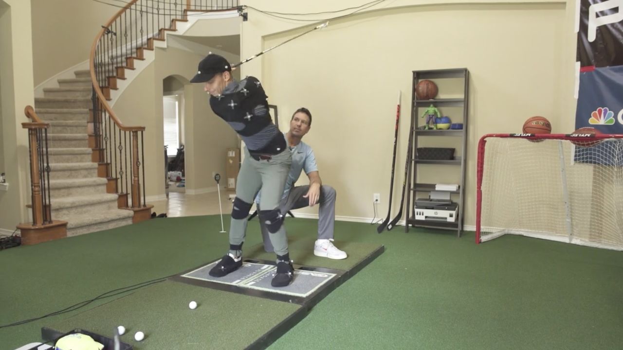 Como helps one of his teaching assistant's with his swing.