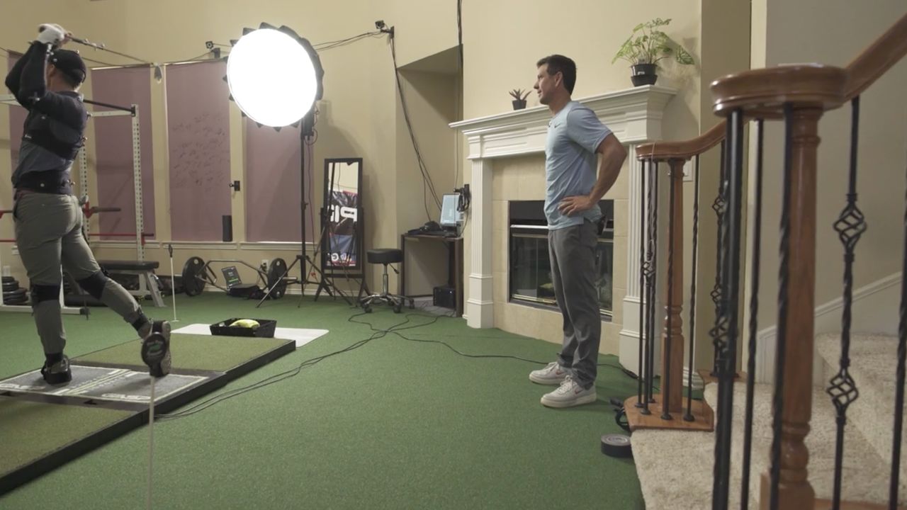 Como stands and watches as his teaching assistant swings.