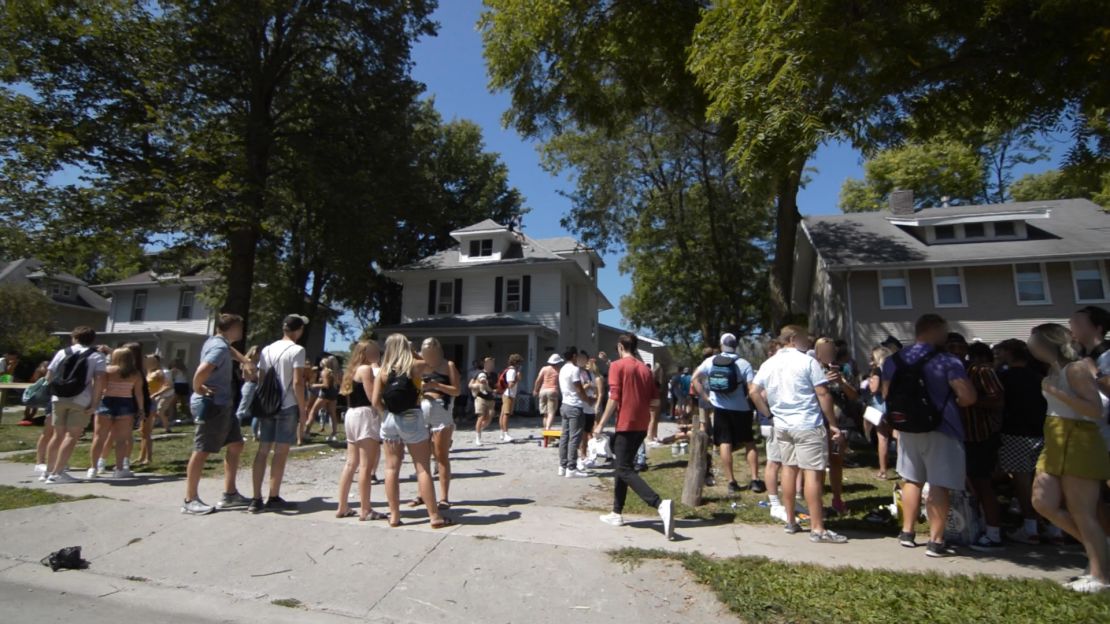 At Iowa State University, students gather in crowds for an "8:01" party. CNN has blurred faces to protect individuals' identities.