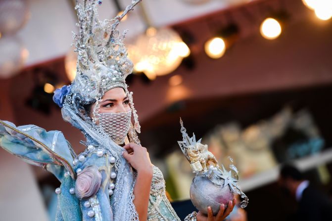 A guest arrives for the opening ceremony in a glitzy Carnival-inspired head-to-toe look, including a crystalline face mask.