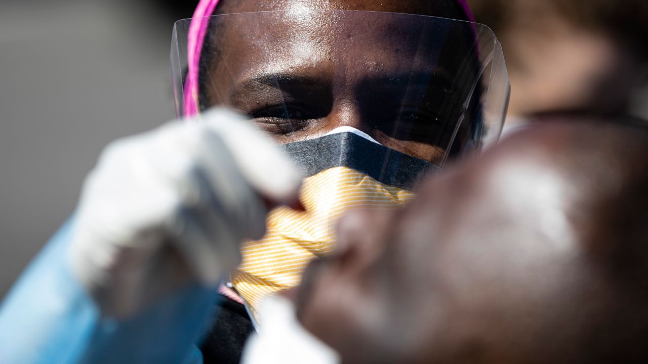 A doctor administers a COVID-19 swab test on a person in a parking lot. (AP Photo/Matt Rourke)
