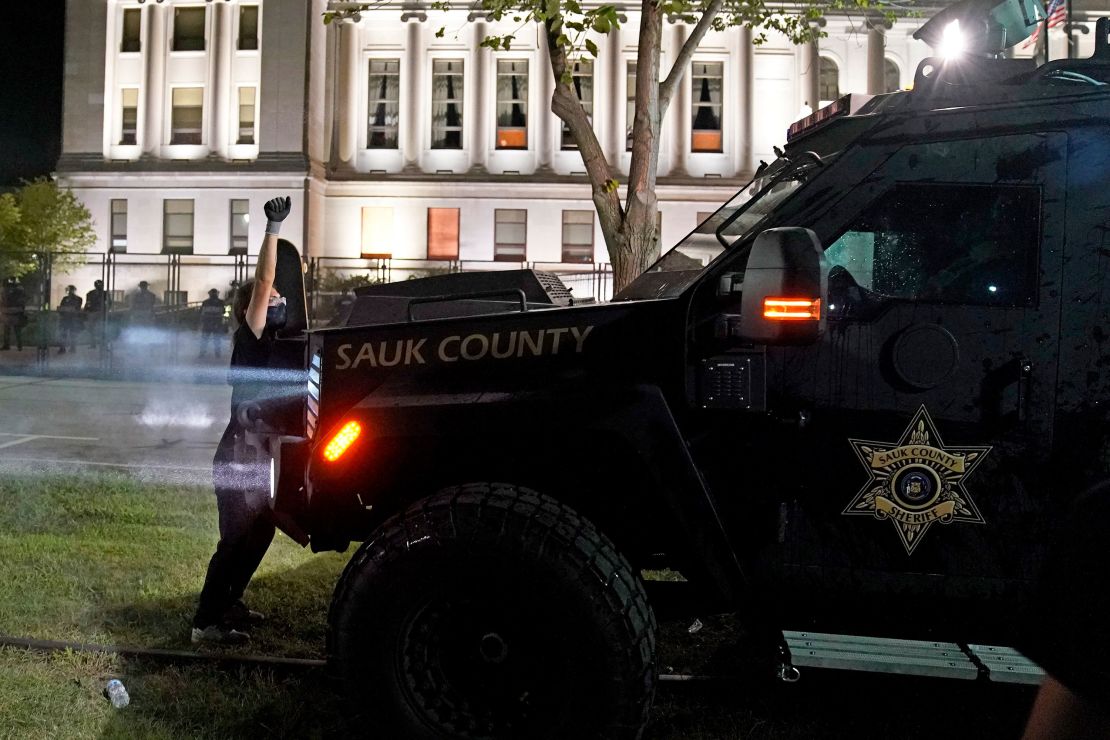 A protester obstructs an armored vehicle attempting to clear the park of demonstrators during clashes outside the Kenosha County Courthouse on August 25.