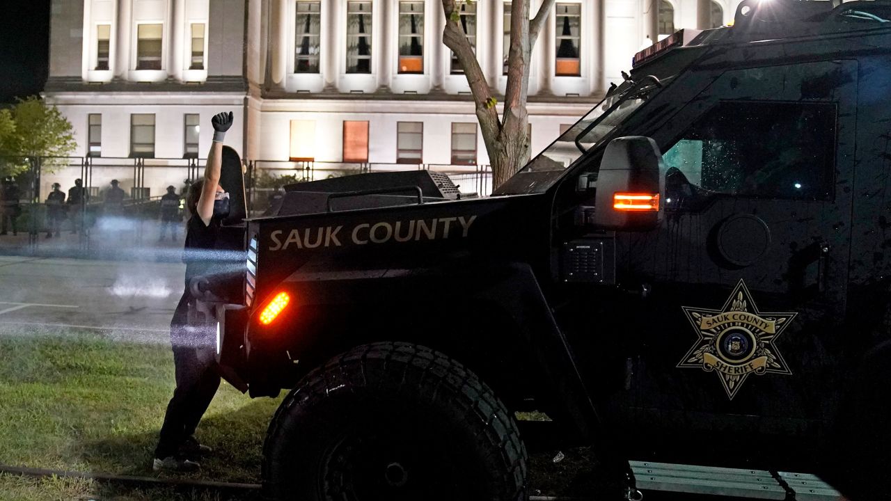 A protester obstructs an armored vehicle attempting to clear the park of demonstrators during clashes outside the Kenosha County Courthouse on August 25.