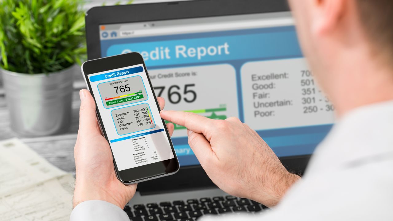 Person checking their credit score on a smartphone and laptop.