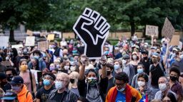 A protester wearing a mask holds a large black power raised fist in the middle of the crowd that gathered at Columbus Circle on June 14 in New York.  This was part of the Warriors of the Garden Peaceful Protest Against President Donald Trump's 74th Birthday that started at Trump International Tower and drew large crowds. 