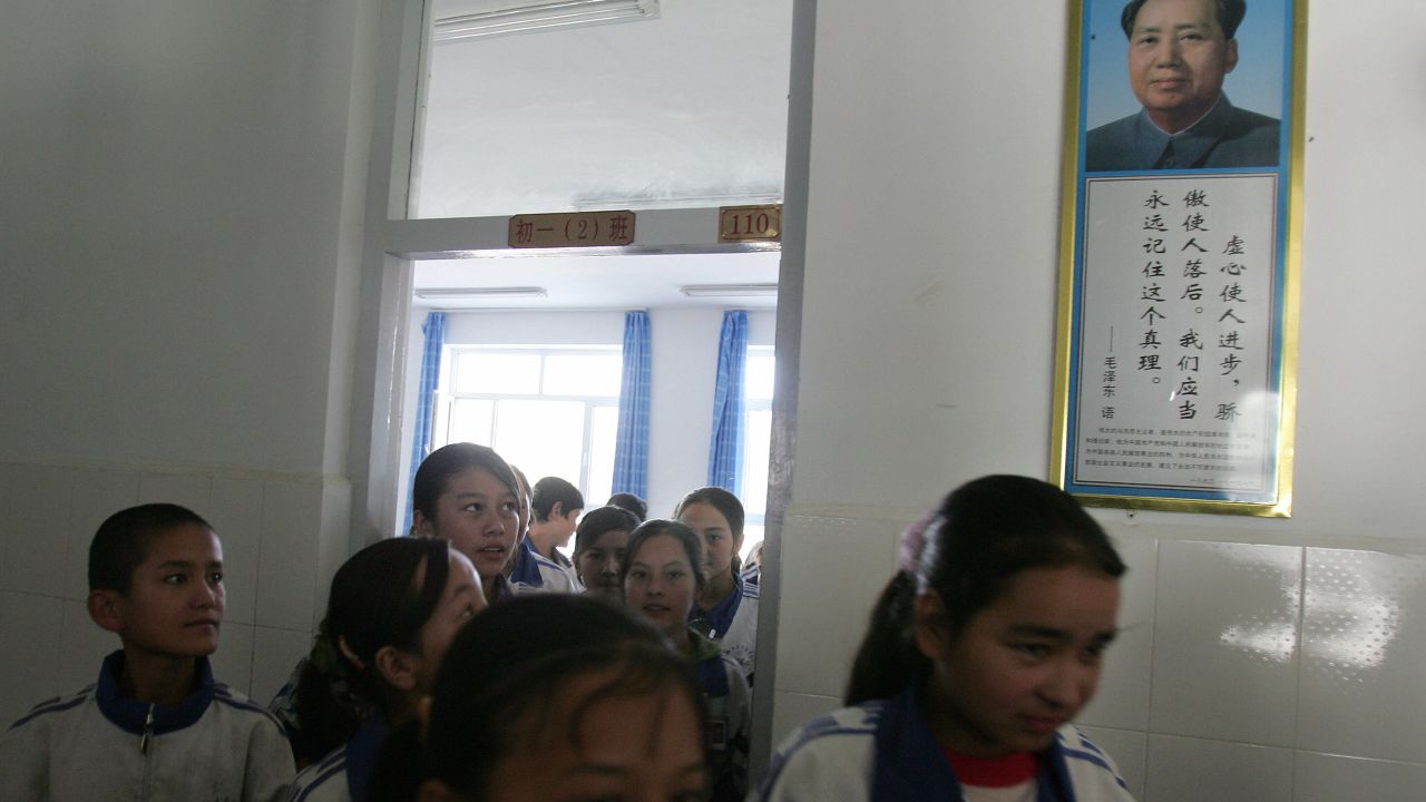 Students walk past a portrait of China's late Chairman Mao Zedong at a bilingual middle school for Uyghur and Han Chinese students in Hotan, Xinjiang in 2006.