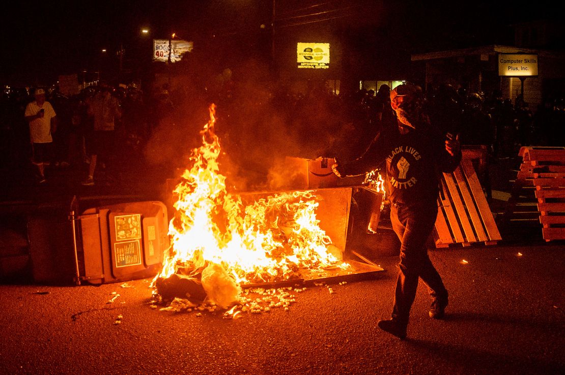 A protester passes a dumpster fire on Saturday, Sept. 5, 2020, during a demonstration in Portland.