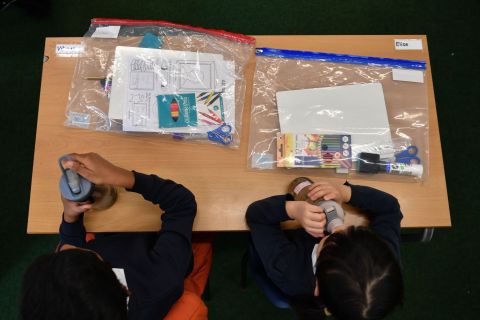 Students sit together on their first day of school in London on September 3. Their belongings had to be contained in plastic bags as part of new regulations.