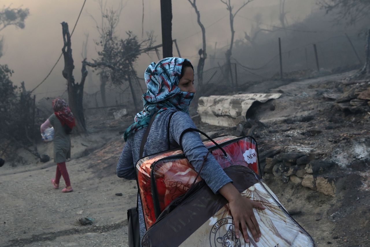 A woman carries her belongings in the aftermath of the fire.