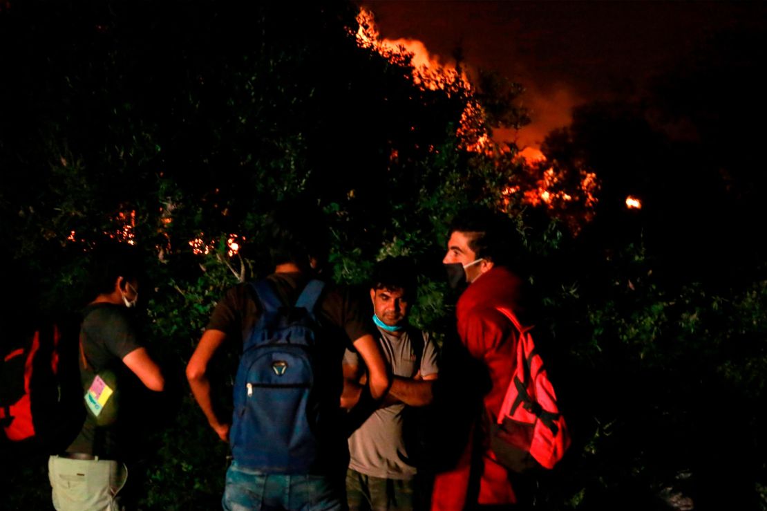 Migrants stand outside the Moria camp on the island of Lesbos as a major fire ravages the site. 