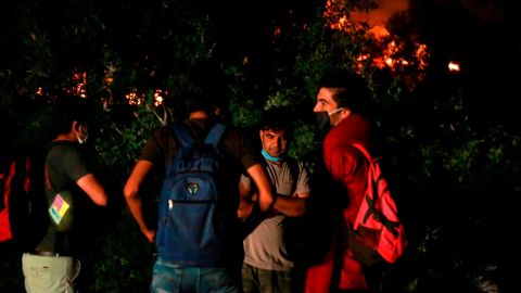 Migrants stand outside the Moria camp on the island of Lesbos as a major fire ravages the site.