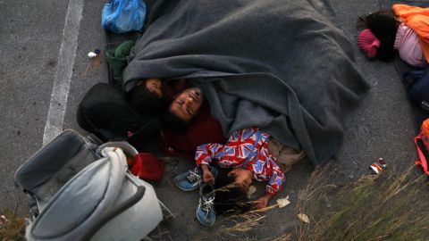 A family sleeps at a parking space, following the fire at the Moria camp.