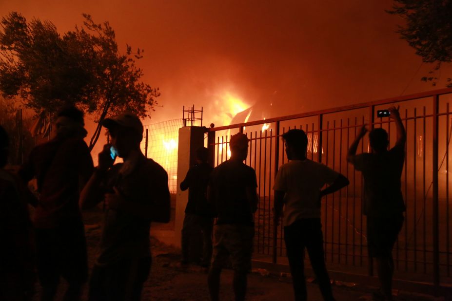 Migrants stand outside the Moria camp as it burns.