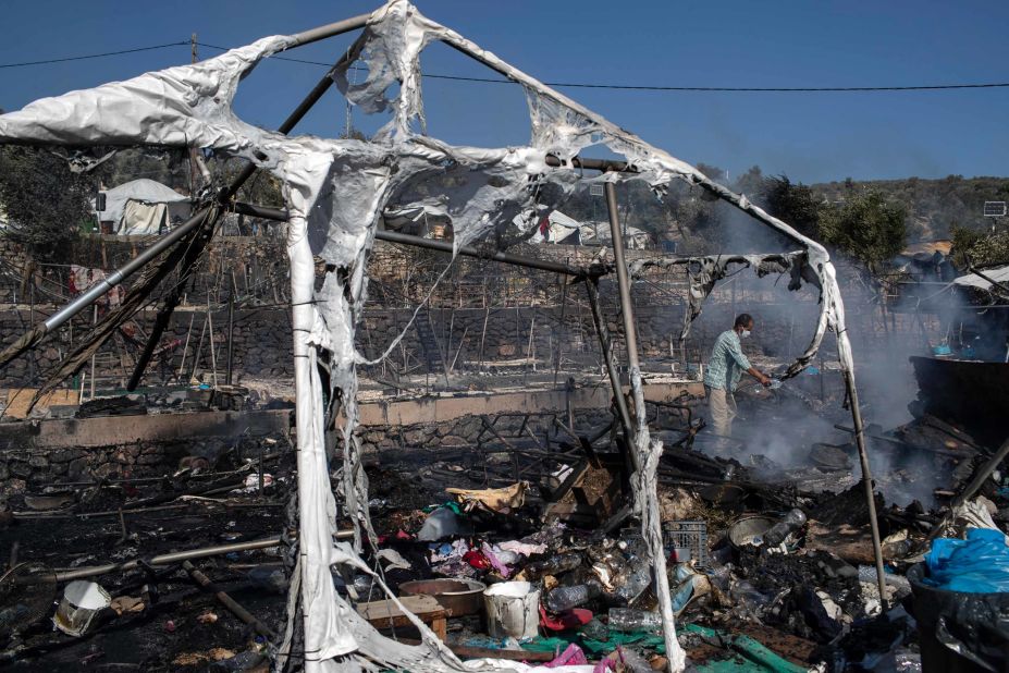 A camp resident pours water over burning debris.