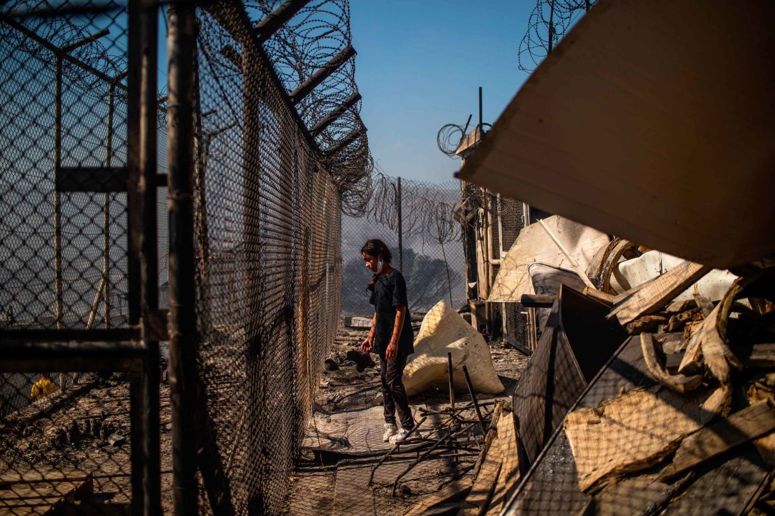 A girl stands amid rubble in the burnt camp after the fires Greek authorities believe were lit by residents.