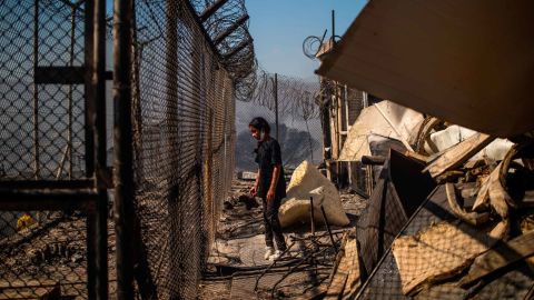 A girl stands amid rubble in the burnt camp after the fires Greek authorities believe were lit by residents.