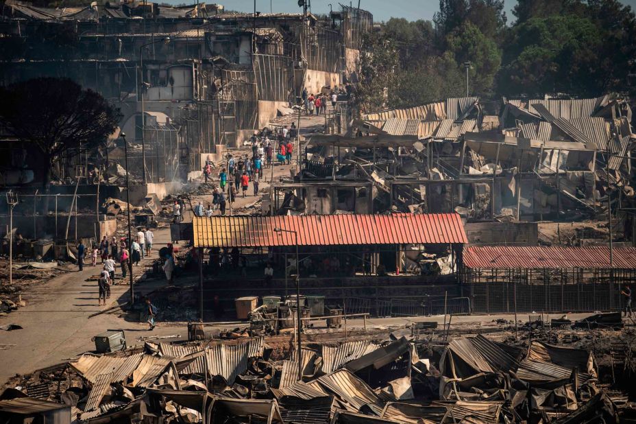 People walk through the charred remains of the camp on September 9.