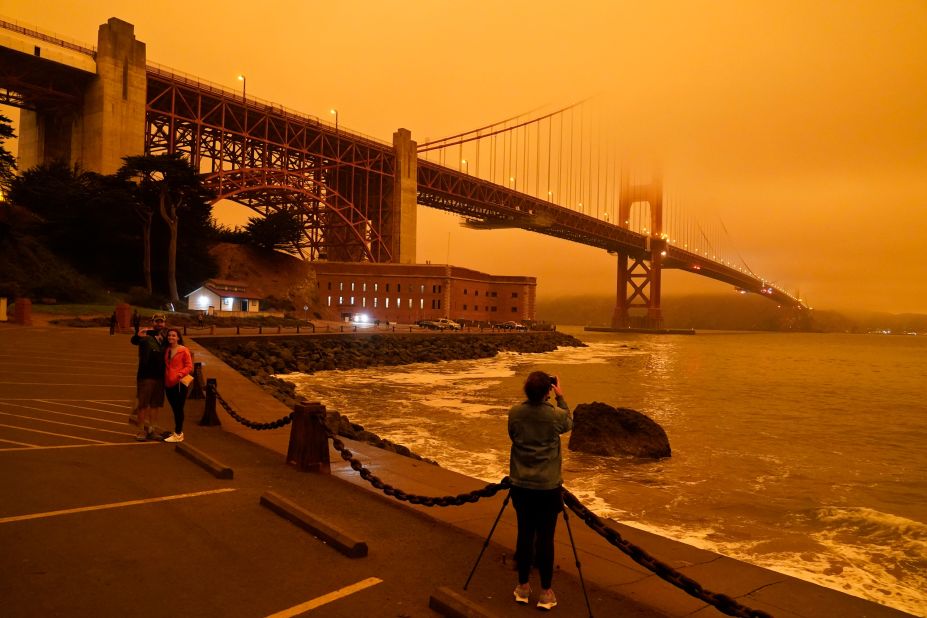 People stop to take pictures of the Golden Gate Bridge as it is affected from smoke by nearby wildfires on September 9, 2020.