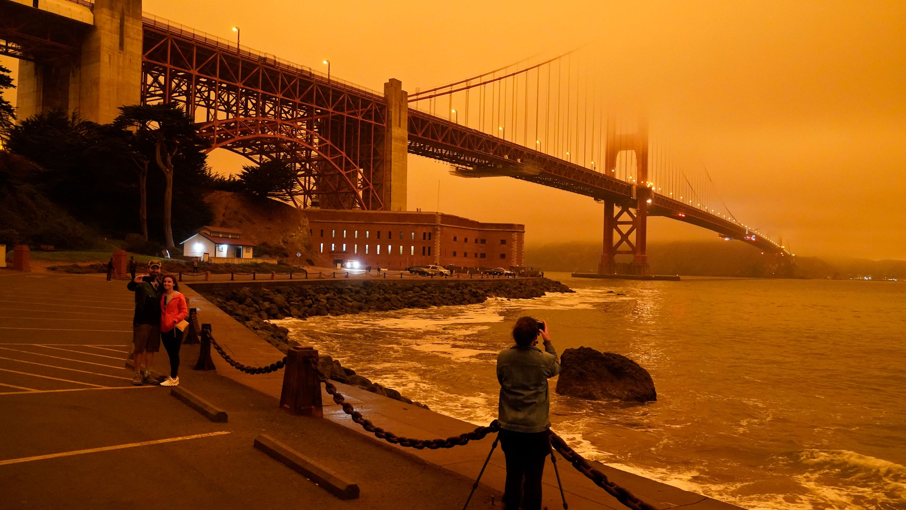 People stop to take pictures of the Golden Gate Bridge as it is affected from smoke by nearby wildfires on September 9, 2020.