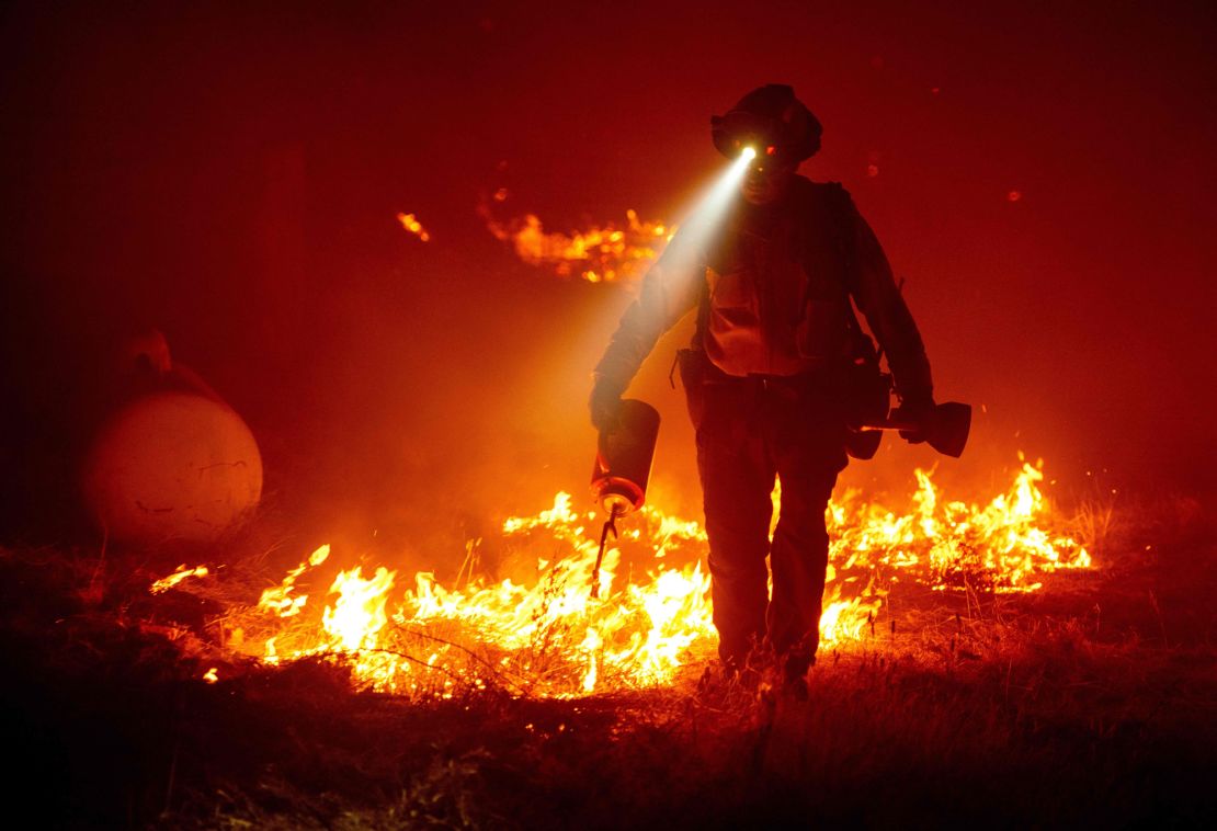 Firefighters cut defensive lines and light backfires to protect structures behind a CalFire fire station during the Bear fire, part of the North Lightning Complex fires in the Berry Creek area of unincorporated Butte County, California on September 9, 2020. 
