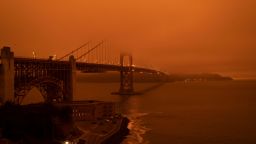 Cars drive along the Golden Gate Bridge under an orange smoke filled sky at midday in San Francisco, California on September 9, 2020. - More than 300,000 acres are burning across the northwestern state including 35 major wildfires, with at least five towns "substantially destroyed" and mass evacuations taking place. (Photo by Harold POSTIC / AFP) / The erroneous mention[s] appearing in the metadata of this photo by Harold POSTIC has been modified in AFP systems in the following manner: [Golden Gate Bridge] instead of [San Francisco Bay Bridge]. Please immediately remove the erroneous mention[s] from all your online services and delete it (them) from your servers. If you have been authorized by AFP to distribute it (them) to third parties, please ensure that the same actions are carried out by them. Failure to promptly comply with these instructions will entail liability on your part for any continued or post notification usage. Therefore we thank you very much for all your attention and prompt action. We are sorry for the inconvenience this notification may cause and remain at your disposal for any further information you may require. (Photo by HAROLD POSTIC/AFP via Getty Images)